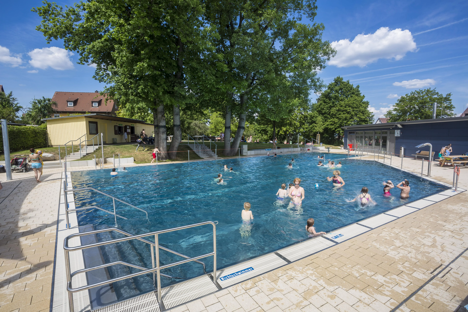 Einige Badegäste planschen im Außenschwimmbecken im Freibad Sillenbuch.