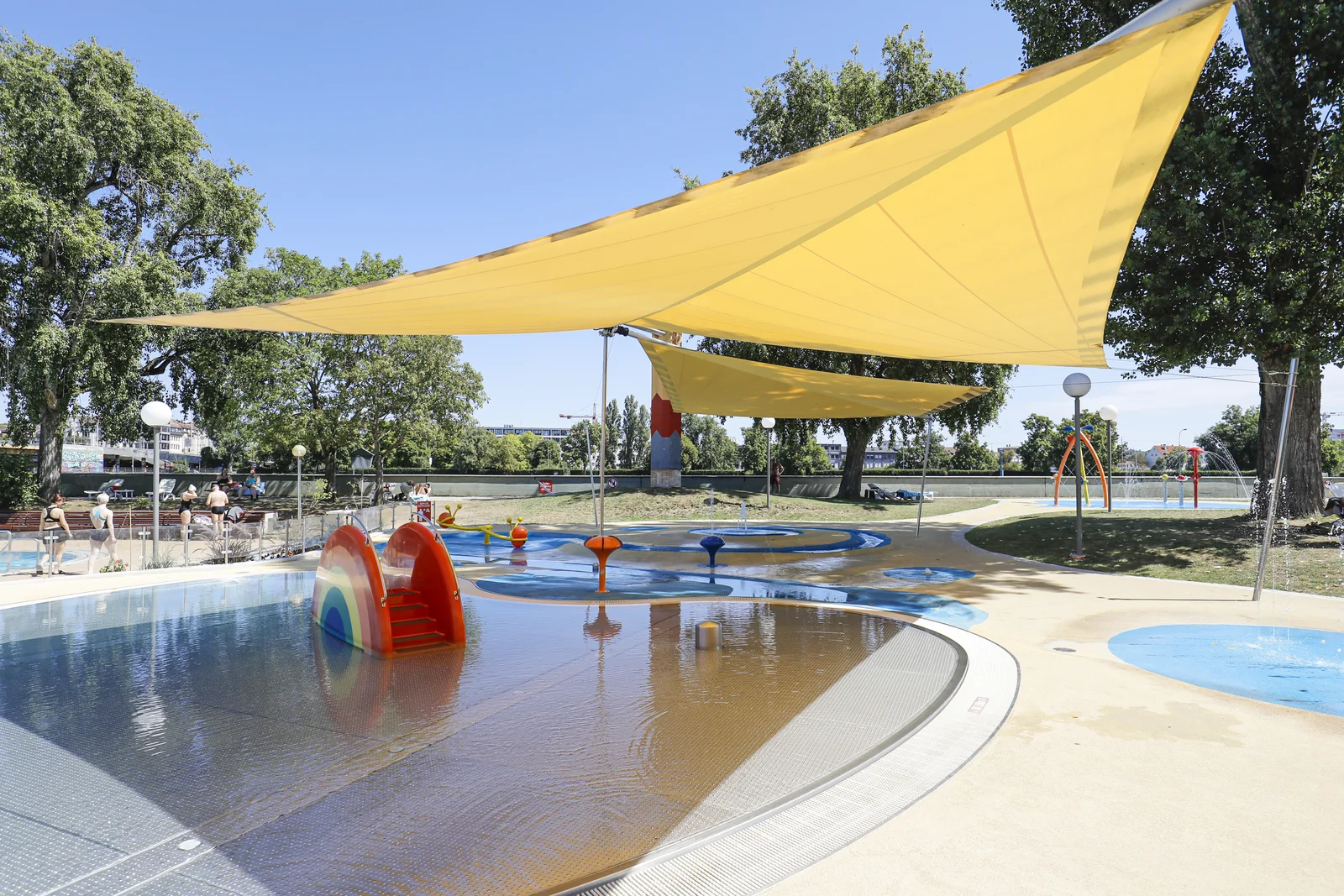 DAS LEUZE Planschbecken mit Wasserrutschbahn Blick auf das Planschbecken mit Wasserrutschbahn und Sonnensegel im LEUZE. Rechts auf dem Bild ist Kinderspielbereich mit Wasserspielplatz.