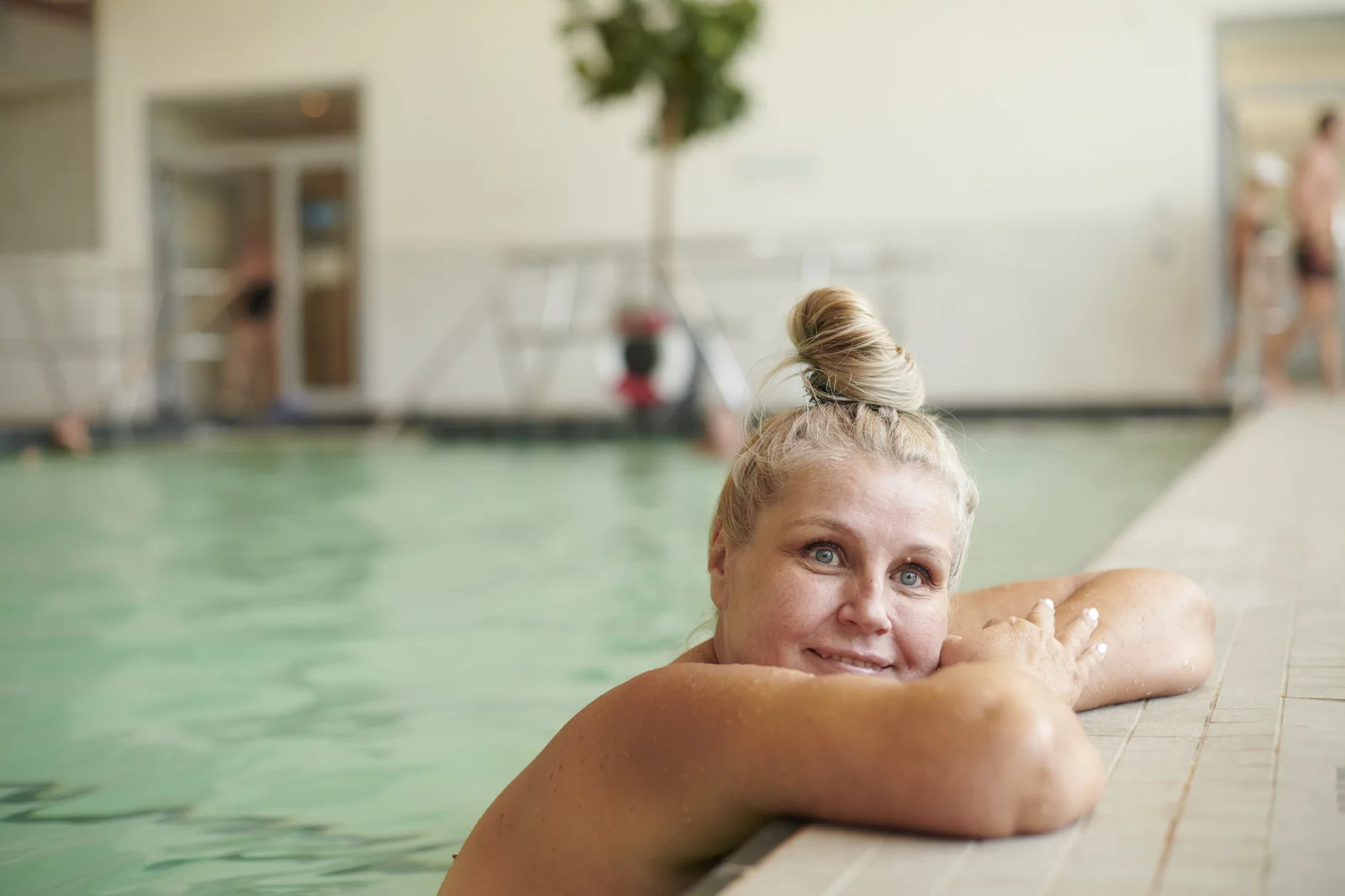 Eine Frau ruht sich im Innenbecken aus. Die Arme bequem am Beckenrand abgelegt.